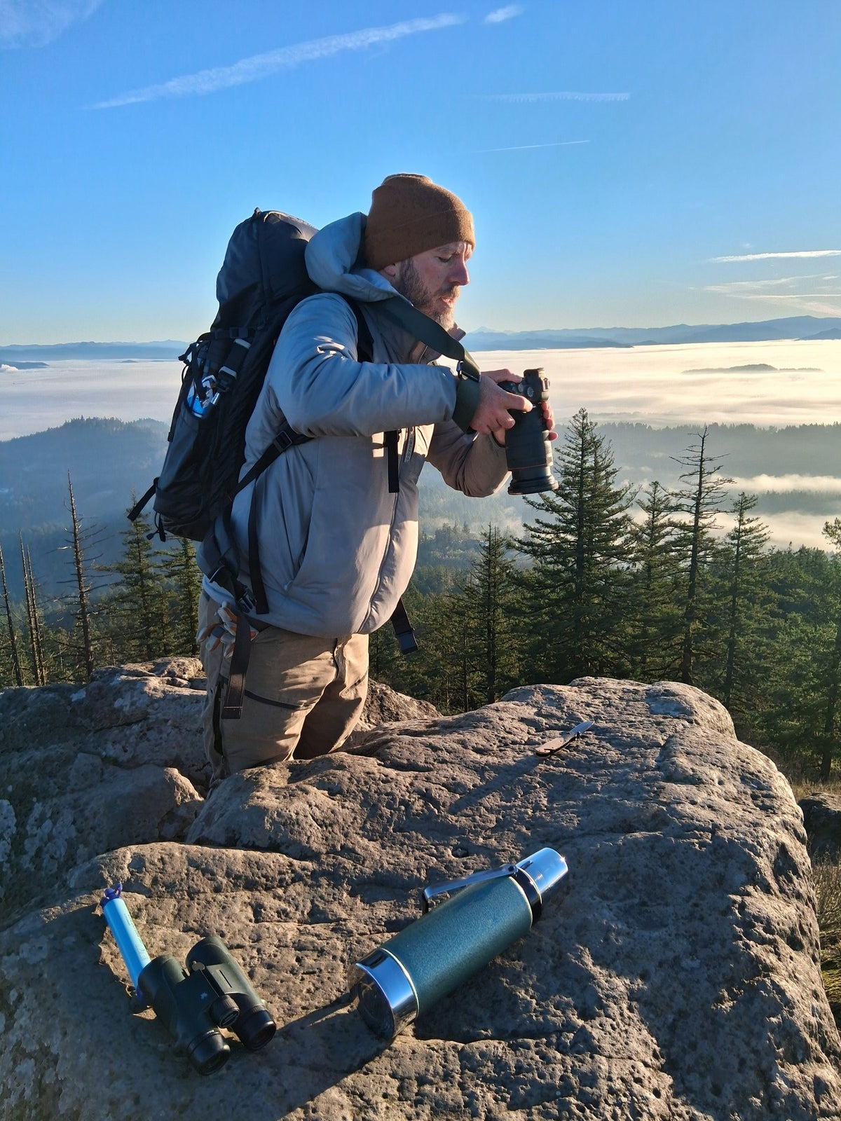 Photographer Ryan Heck with a camera on a rocky summit above the clouds