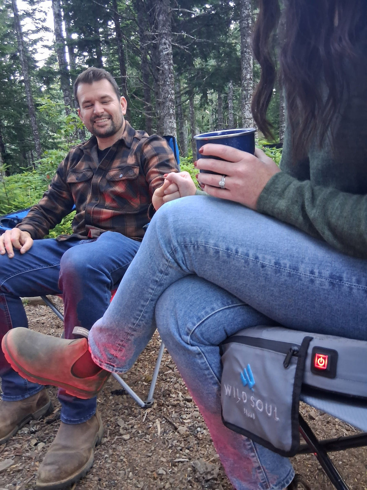 Friends sitting at a forest campsite on NextPad Camp heated seat cushions