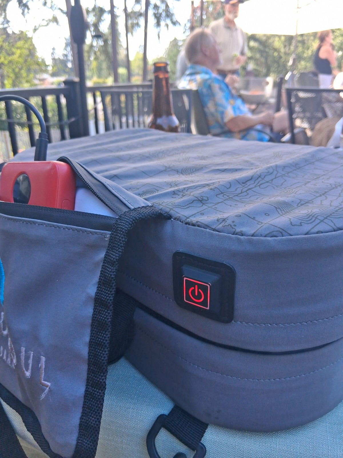 Close-up of a NextPad Camp heated seat cushion and its power button on an outdoor patio seat