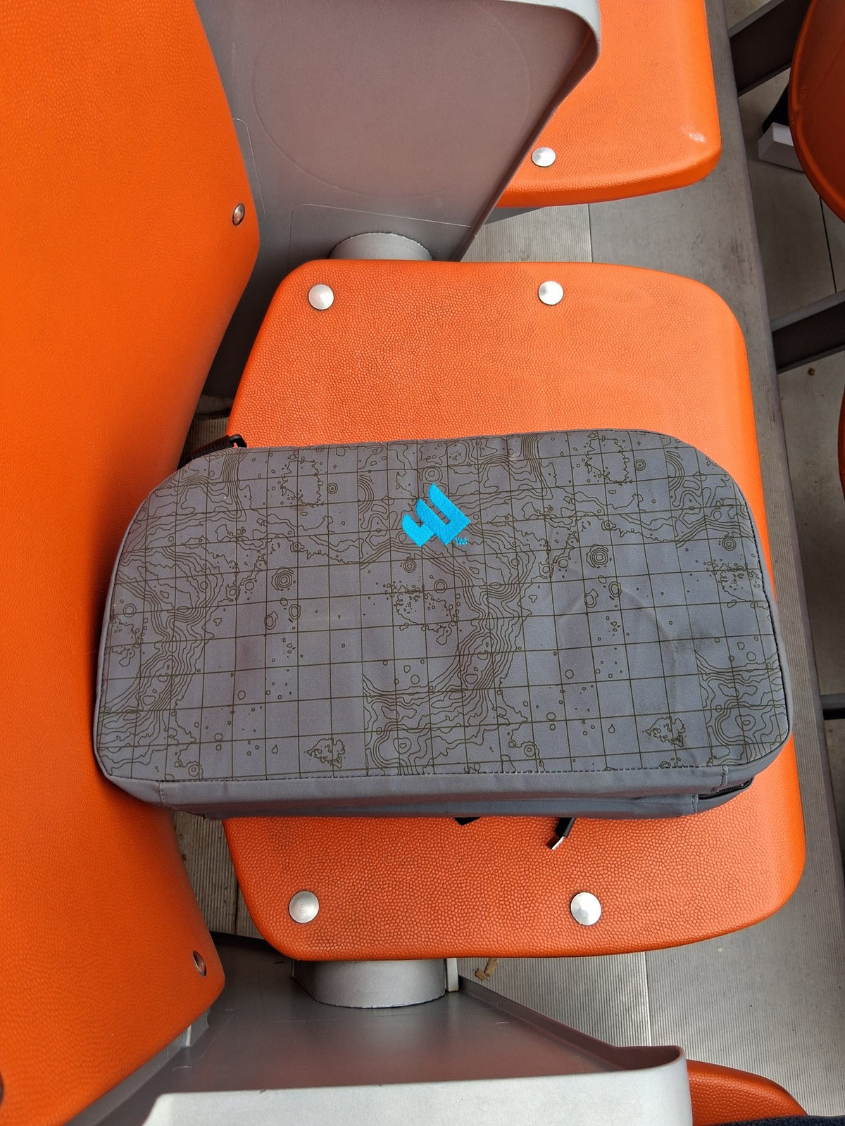 NextPad Camp seat cushion on an orange stadium seat