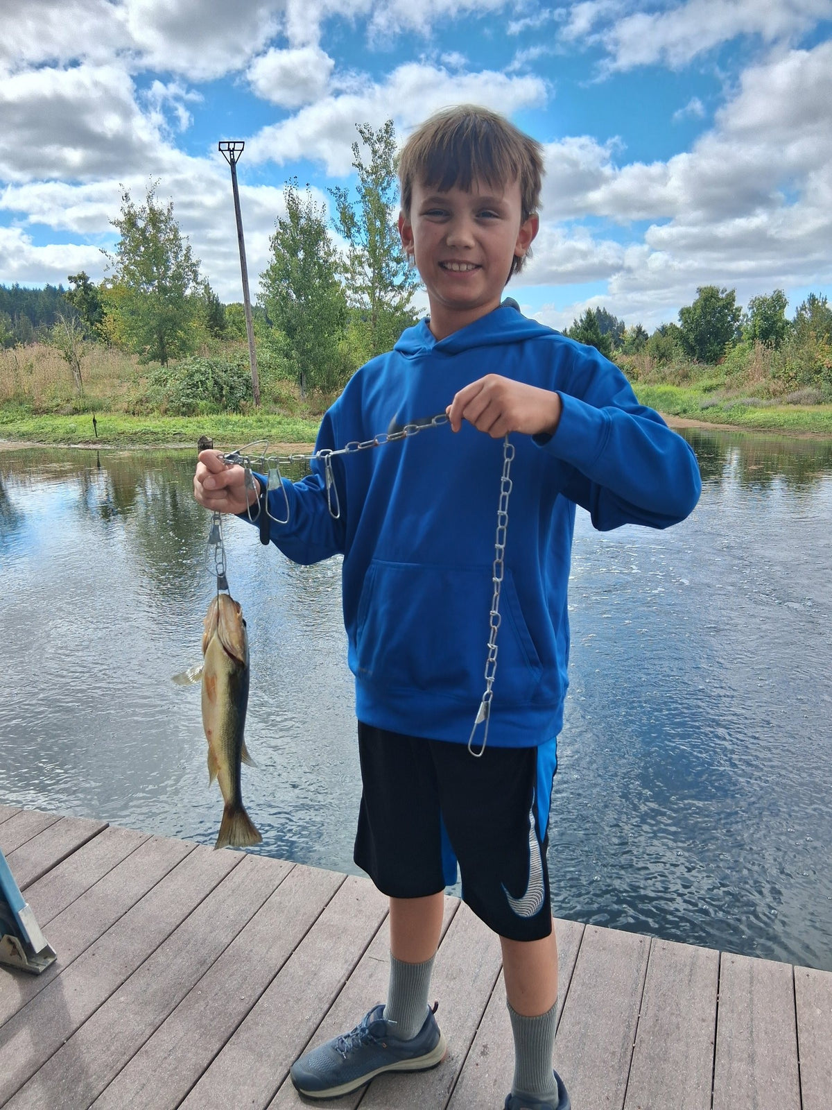 Boy holding up a fish he caught on a pond dock