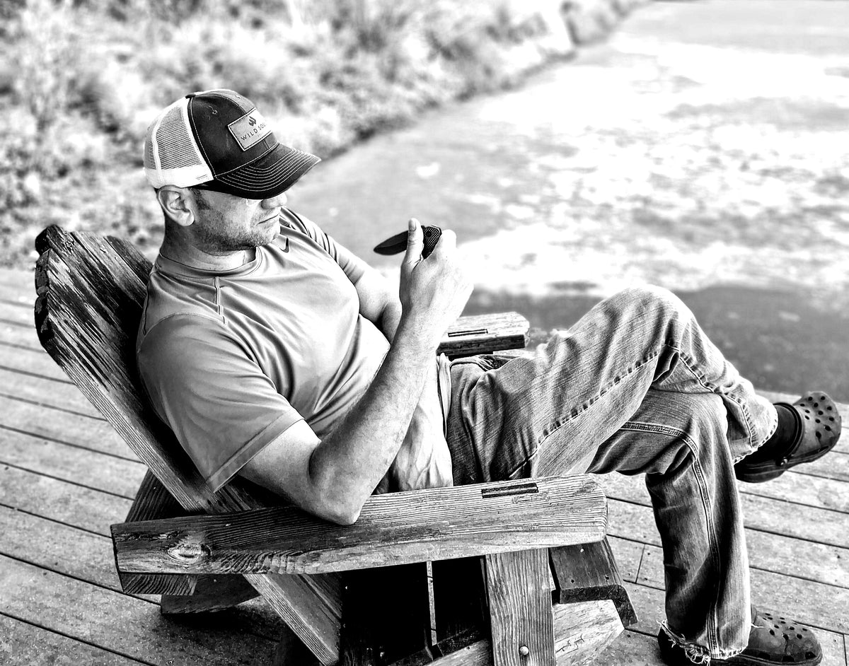 Wild Soul Brand founder relaxing in an Adirondack chair with a Ridgeblade folding knife, black and white portrait