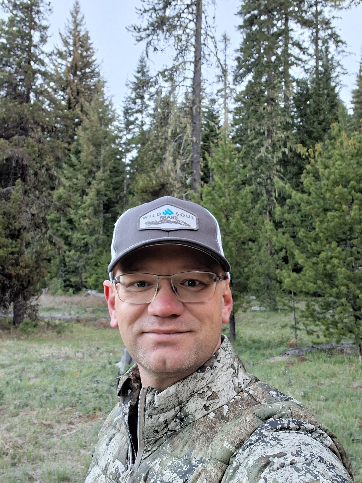 Founder in camo and a Wild Soul hat in a pine forest in the early morning