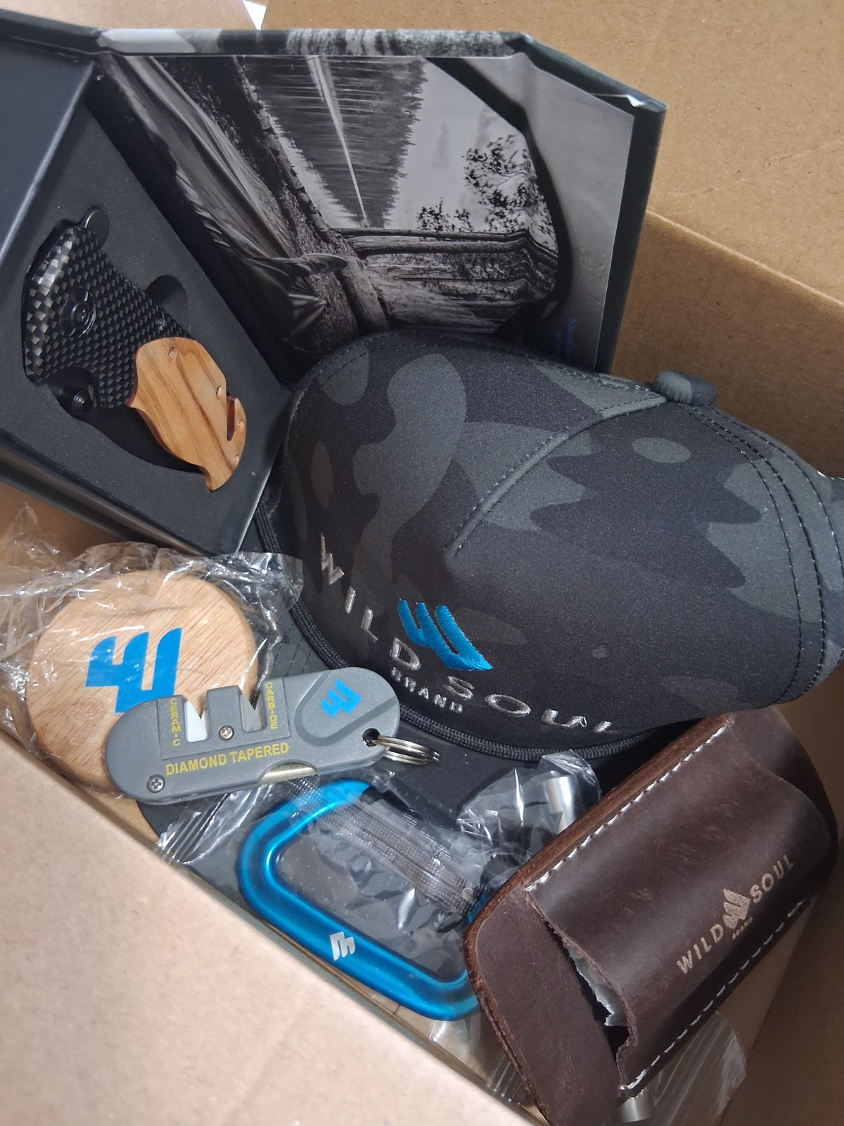 Box packed with a Wild Soul Brand hat, carabiners and gear